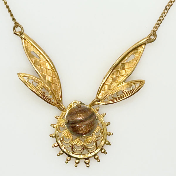 A gold filigree pendant necklace featuring two leaf-shaped elements and a central oval brown stone, shown against a plain white background.