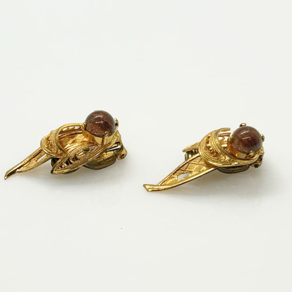 A pair of vintage gold-toned wing-shaped earrings with round brown cabochon gemstones, displayed on a clean white background.