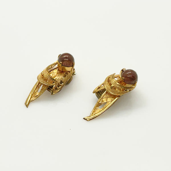 A pair of vintage gold-toned winged earrings with round brown cabochon stones, displayed on a clean white background.