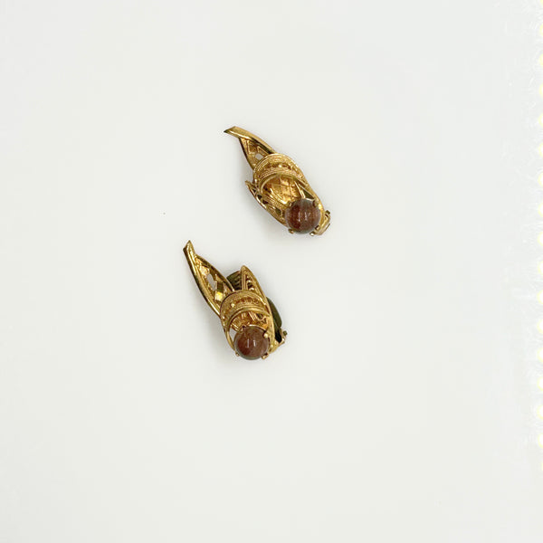 A pair of vintage gold-tone winged earrings with round brown cabochon gemstones, displayed on a clean white background.