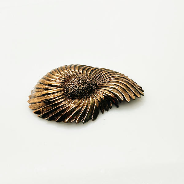 Vintage Tortolani copper-toned shell brooch featuring a textured, swirling modernist design reminiscent of a nautilus shell with a central cluster of dense, nugget-like details against a solid white background