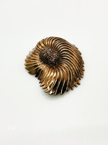 Vintage Tortolani copper-toned shell brooch featuring a textured, swirling modernist design reminiscent of a nautilus shell with a central cluster of dense, nugget-like details against a solid white background