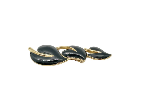 This stylish Trifari brooch features three black enamel leaves and gold-tone metal accents. Dating from the 1980s-1990s, it's part of Trifari's well-documented series of black enamel and gold-tone leaf brooches. 