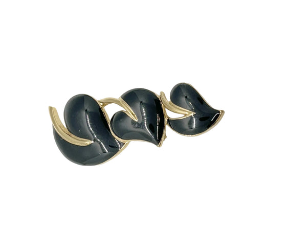 This stylish Trifari brooch features three black enamel leaves and gold-tone metal accents. Dating from the 1980s-1990s, it's part of Trifari's well-documented series of black enamel and gold-tone leaf brooches. 