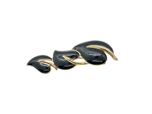 This stylish Trifari brooch features three black enamel leaves and gold-tone metal accents. Dating from the 1980s-1990s, it's part of Trifari's well-documented series of black enamel and gold-tone leaf brooches. 