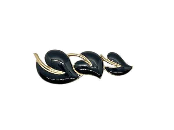 Meet your new favorite accessory! This gorgeous Trifari brooch showcases three beautifully crafted black enamel leaves accented with warm gold-tone metal—a timeless design from the 1980s-1990s era.