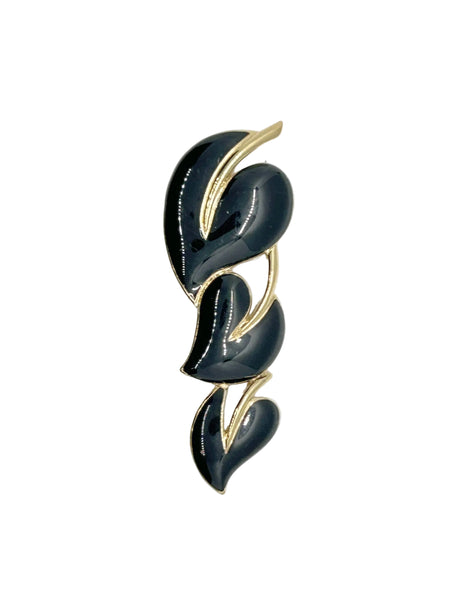 This stylish Trifari brooch features three black enamel leaves and gold-tone metal accents. Dating from the 1980s-1990s, it's part of Trifari's well-documented series of black enamel and gold-tone leaf brooches. 
