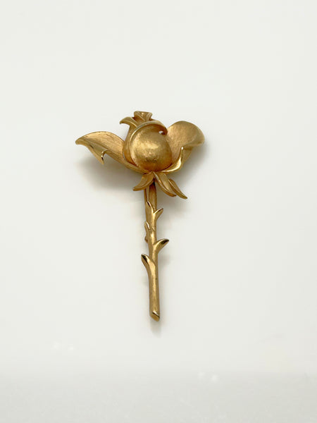 Vintage Crown Trifari gold-tone long-stem rose brooch featuring a detailed, textured matte rosebud on a thorny gold stem against a clean white background.