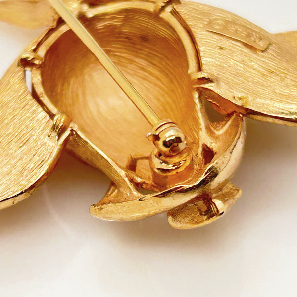 Vintage Crown Trifari gold-tone long-stem rose brooch featuring a detailed, textured matte rosebud on a thorny gold stem against a clean white background.