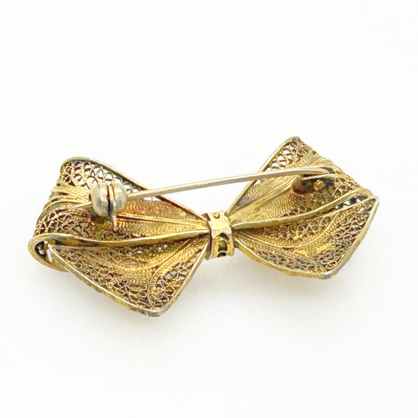Vintage gold filigree bow-shaped brooch with intricate openwork wire detailing, measured at 1.75 inches, displayed on a clean white background.
