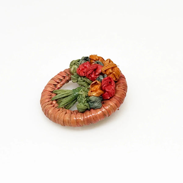 This beautiful antique brooch, likely dating back to the early 1900s, is quite rare. It showcases a charming design with colored straw wrapped around a circular frame. Inside, you'll find a delicate, hand-crafted tree or bouquet made from fine threads.