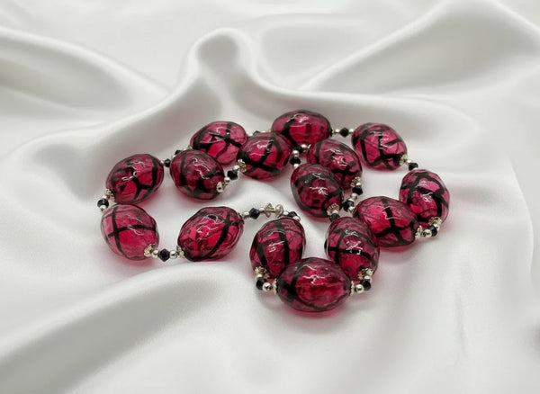 Express your unique style with this stunning Vintage Clear Magenta and Black Striped Blown Glass Beads Necklace. Its cool and smooth touch will captivate your senses, while the mesmerizing dark swirls add a touch of mystery and intrigue.