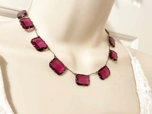 Admire the timeless beauty of our Graceful Vintage Czech Violet Clear Stones Necklace. Handcrafted with thirteen emerald cut purple clear stones encased in intricately detailed frames, this elegant necklace is a true work of art. With a length of approximately 15", it is a delicate and sophisticated addition to any outfit. Experience luxury and exclusivity with this exquisite piece, in immaculate condition.