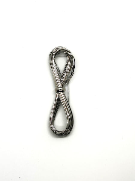 A silver-toned multi-strand wire bow brooch, featuring an infinity-shaped loop silhouette cinched with a smooth central band, displayed against a plain white background.