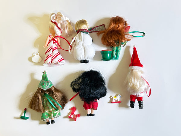 Lot of six loose vintage 2001 Mattel Barbie Kelly Club Christmas holiday ornament mini dolls against a white background, including Peppermint Kelly, Tommy as Snowman, Poinsettia Jenny, Christmas Tree Chelsie, Santa Claus Tommy, and a doll in a red velvet winter fur coat with mini holiday toys.