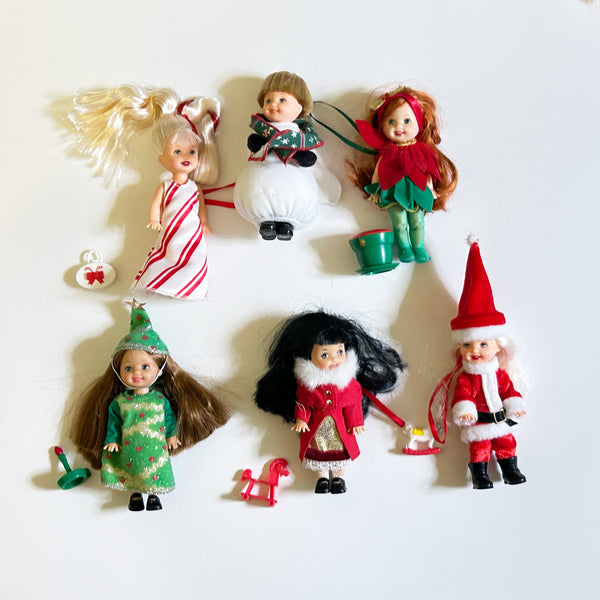 Lot of six loose vintage 2001 Mattel Barbie Kelly Club Christmas holiday ornament mini dolls against a white background, including Peppermint Kelly, Tommy as Snowman, Poinsettia Jenny, Christmas Tree Chelsie, Santa Claus Tommy, and a doll in a red velvet winter fur coat with mini holiday toys.