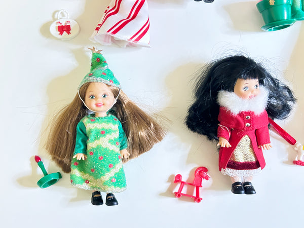 Two 2001 Mattel Kelly Club Christmas dolls, Christmas Tree Chelsie and Caroling Lorena, with miniature holiday accessories on a white background