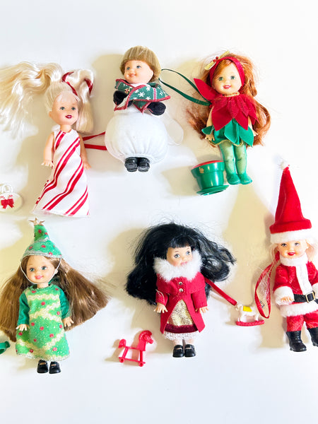 Lot of six loose vintage 2001 Mattel Barbie Kelly Club Christmas holiday ornament mini dolls against a white background, including Peppermint Kelly, Tommy as Snowman, Poinsettia Jenny, Christmas Tree Chelsie, Santa Claus Tommy, and a doll in a red velvet winter fur coat with mini holiday toys.