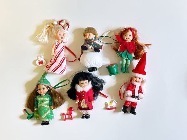 Lot of six loose vintage 2001 Mattel Barbie Kelly Club Christmas holiday ornament mini dolls against a white background, including Peppermint Kelly, Tommy as Snowman, Poinsettia Jenny, Christmas Tree Chelsie, Santa Claus Tommy, and a doll in a red velvet winter fur coat with mini holiday toys.